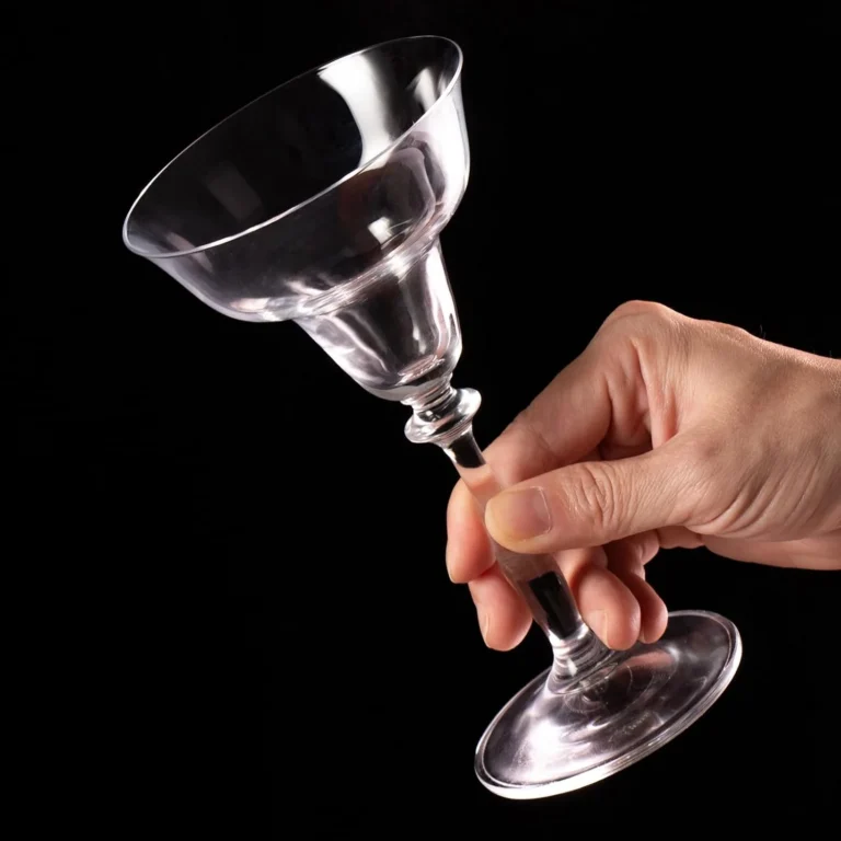 Empty KAMMAK margarita coupe held by its long clear stem