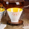 Close view of the orange KAMMAK ceramic tea cup with raised sun motif KAMMAK 7KPSP433N ceramic cup and saucer styled home decor setting image 5