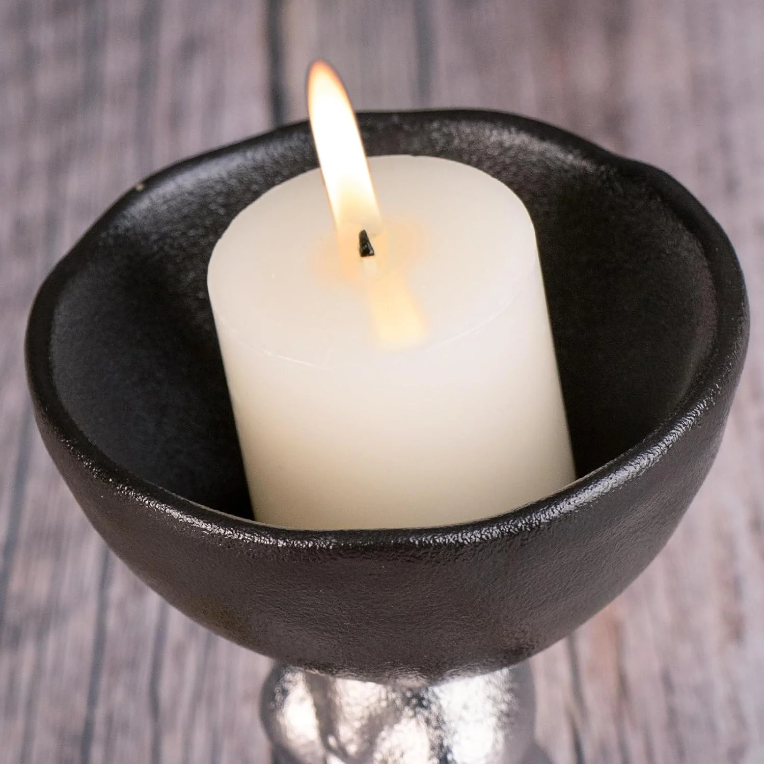 Round black ceramic plate supporting a pillar candle
