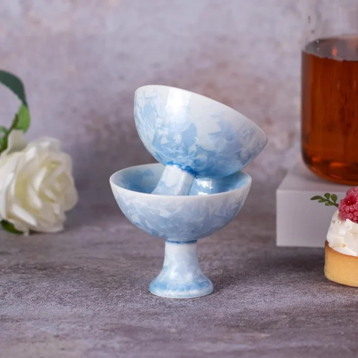 Stacked blue porcelain pedestal tea cups beside a tea setting KAMMAK 7KPSP792N ceramic cup and saucer shape and proportion detail image 3