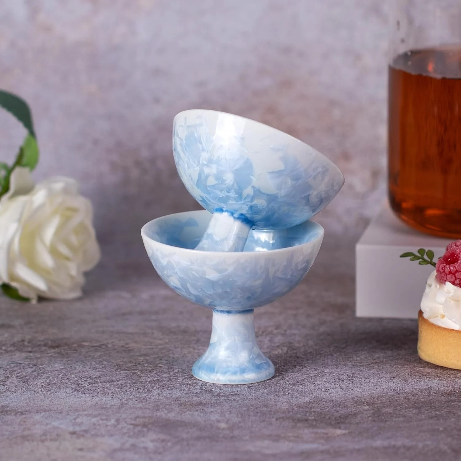 Stacked blue porcelain pedestal tea cups beside a tea setting