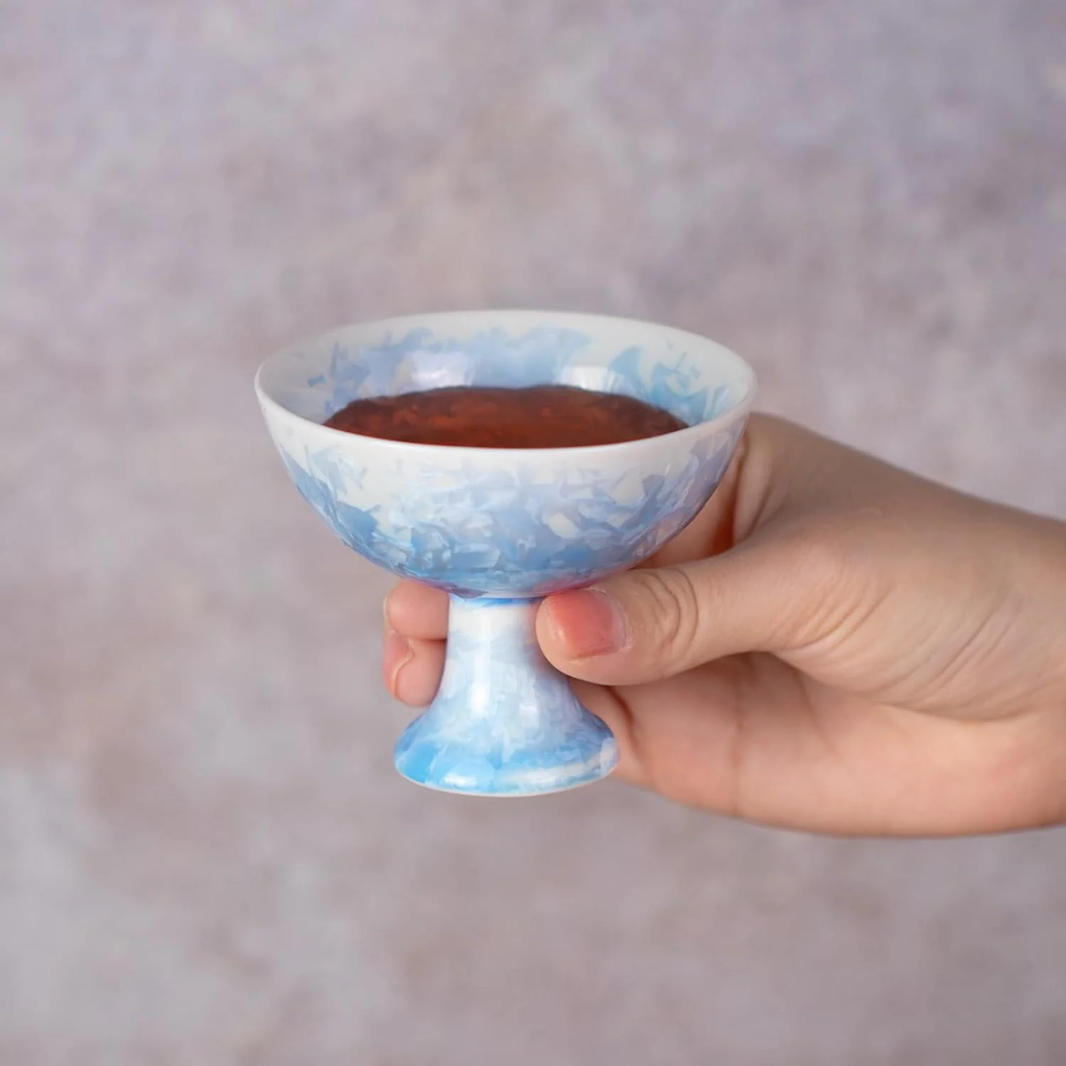 Small blue pedestal tea cup held in one hand