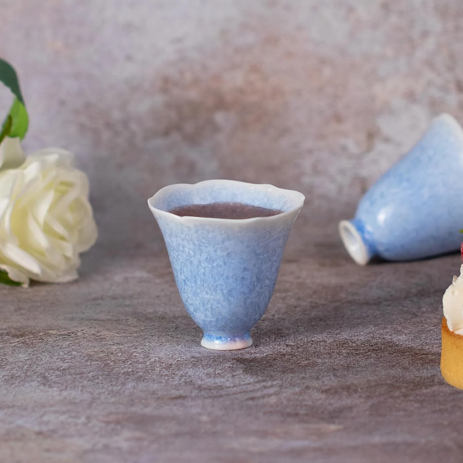 Single blue crystalline glaze petal cup filled with tea