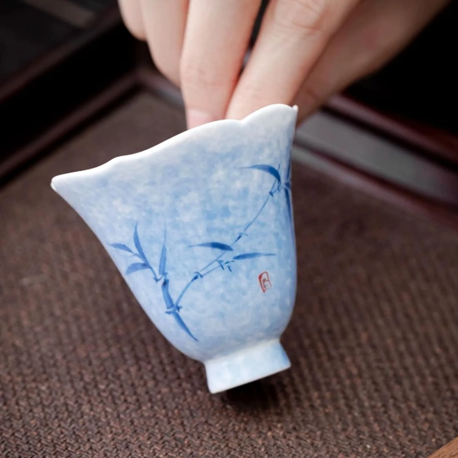 Small blue floral ceramic tea cup held in one hand