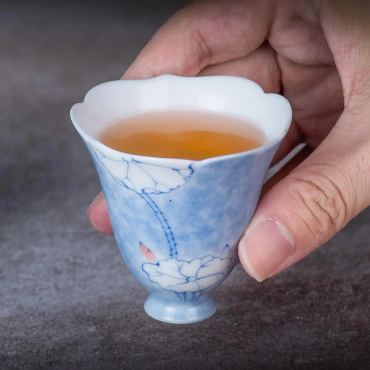 Blue-and-white floral tea cup held with tea inside