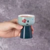 Blue floral pedestal tea cup held in one hand KAMMAK 7KPSP706N ceramic cup and saucer scale and proportion view image 6