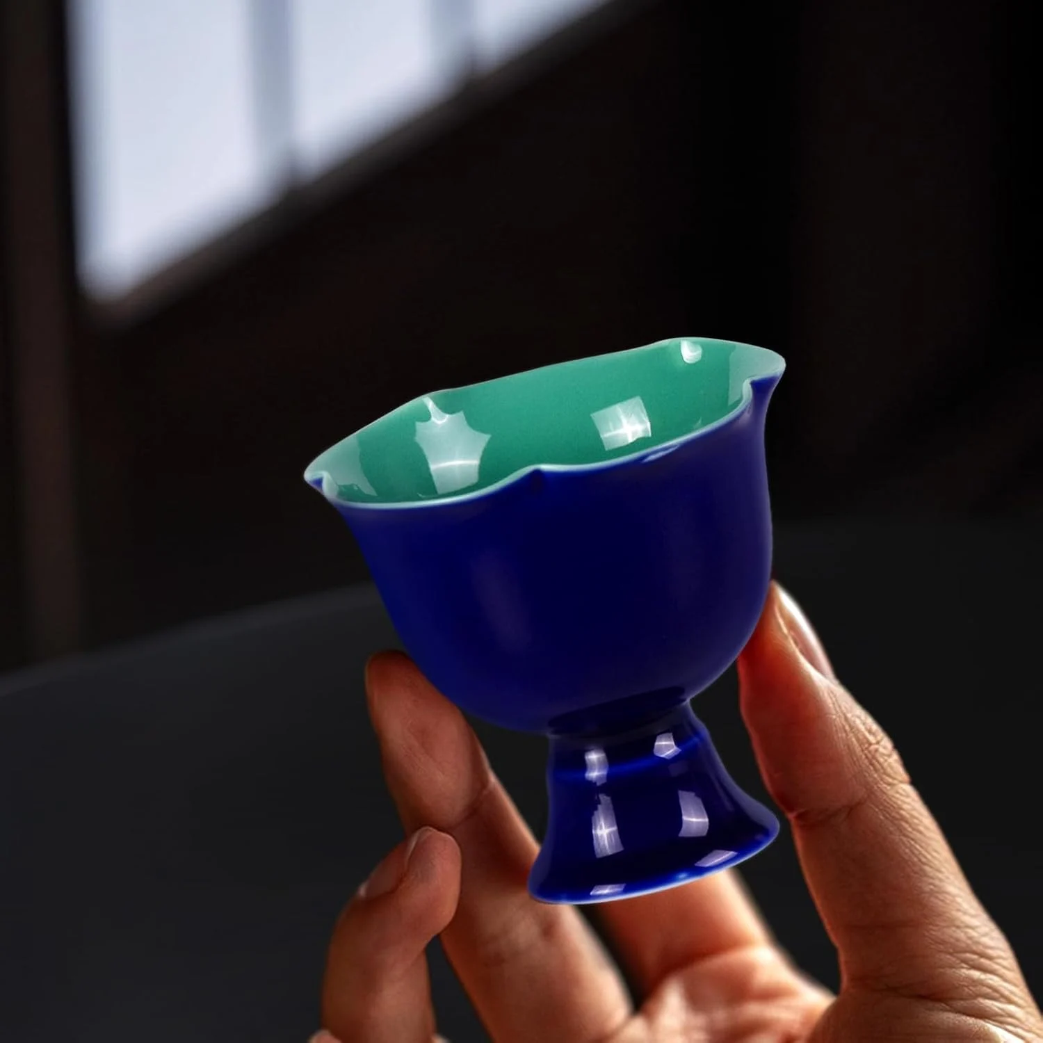 Dark blue scalloped tea cup held in one hand