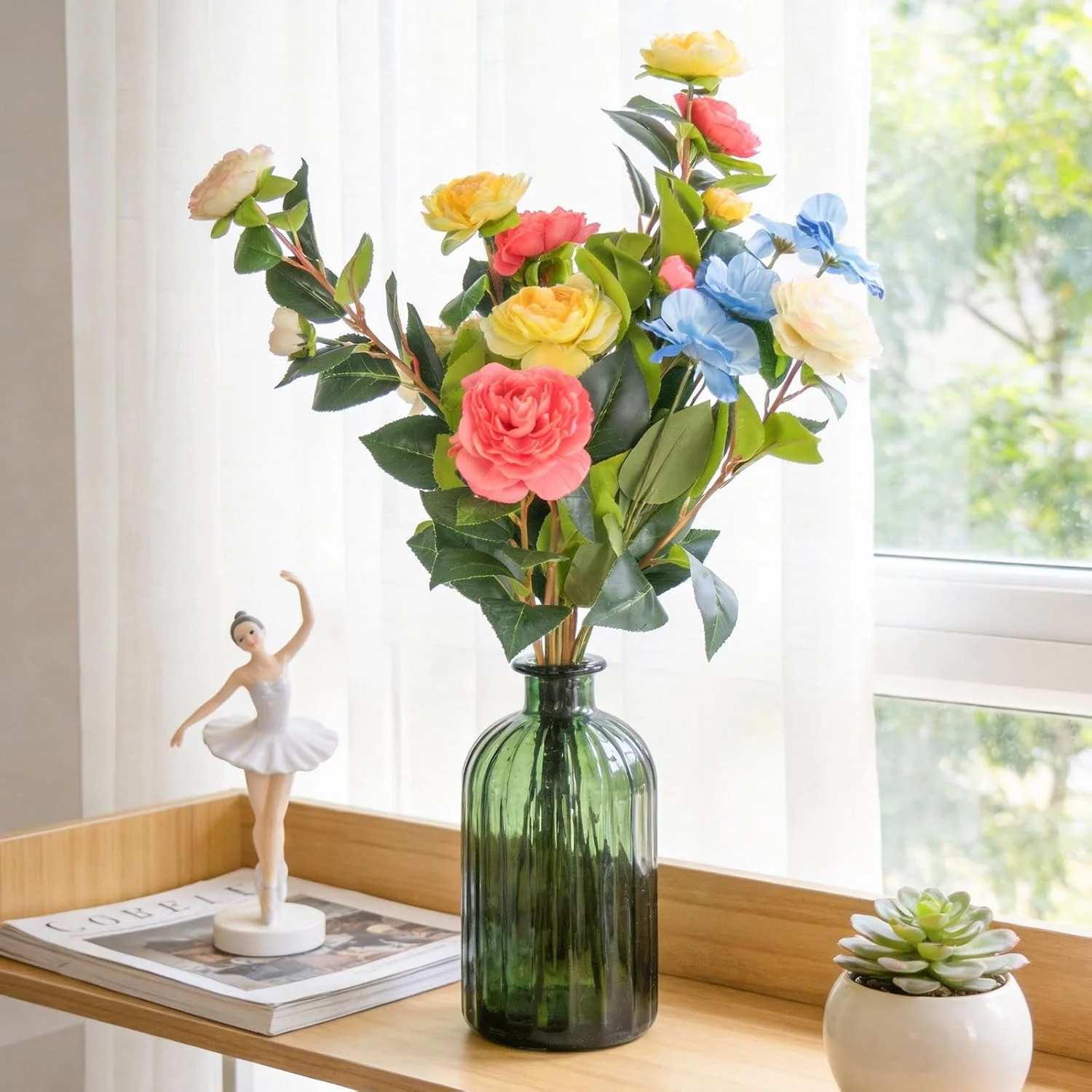 Tall colorful flower stems in a green glass bottle