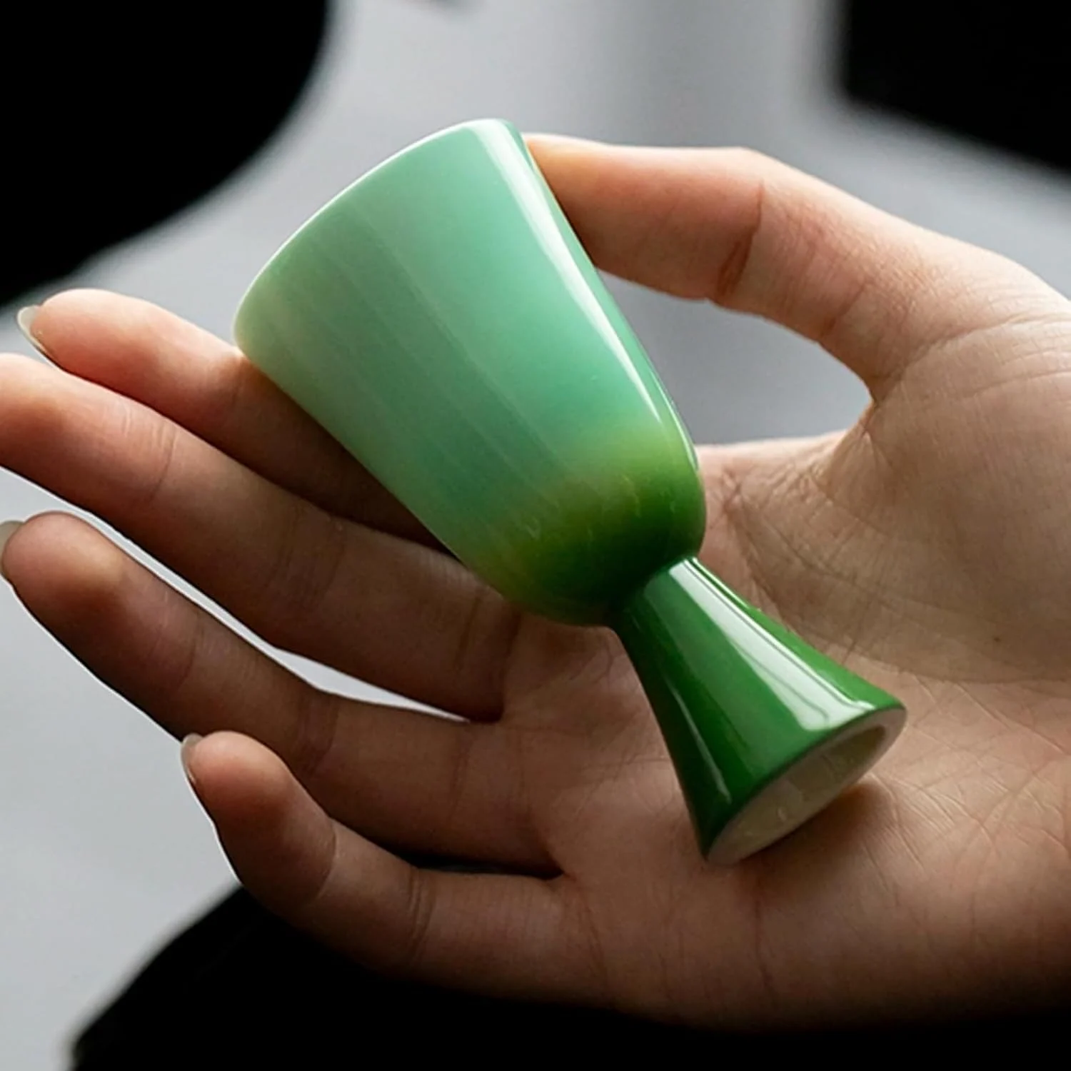 Petite green stemmed tea cup held in one hand