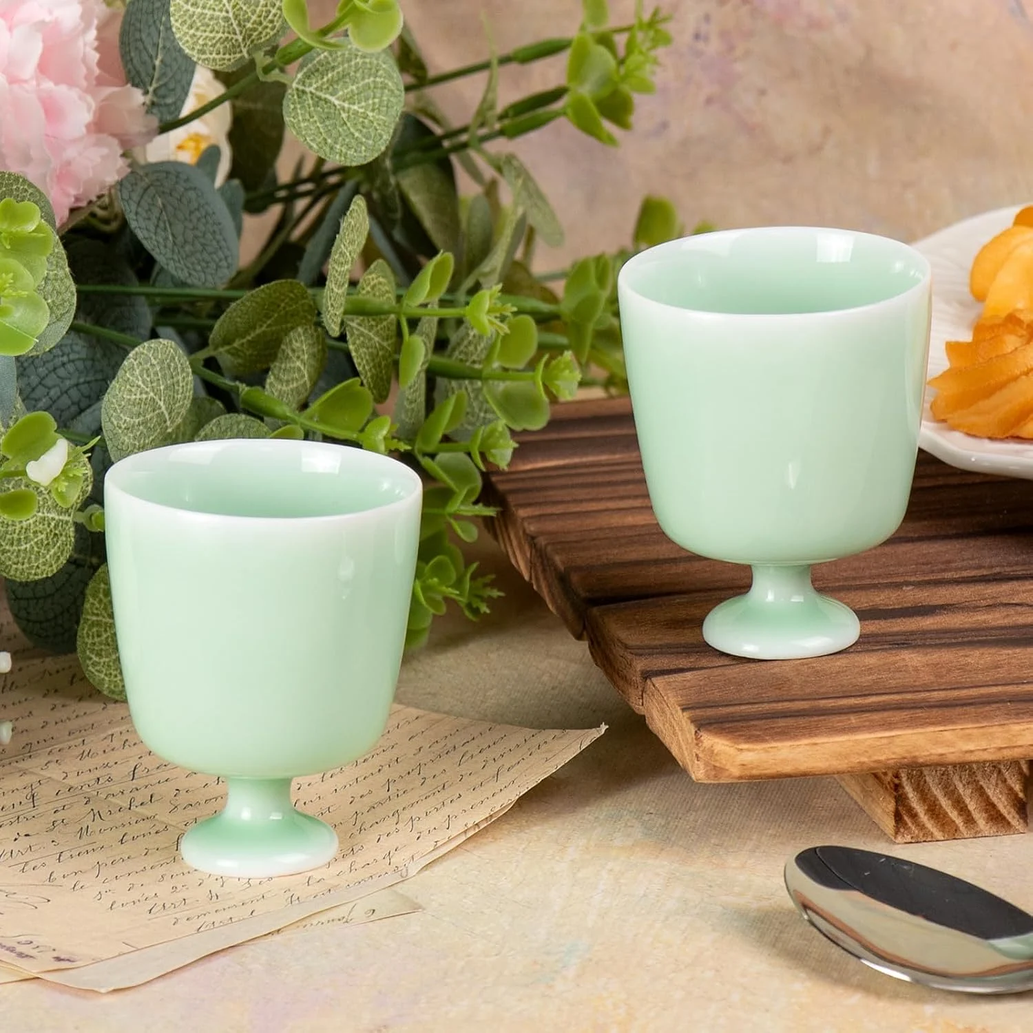 Two mint green pedestal tea cups arranged together