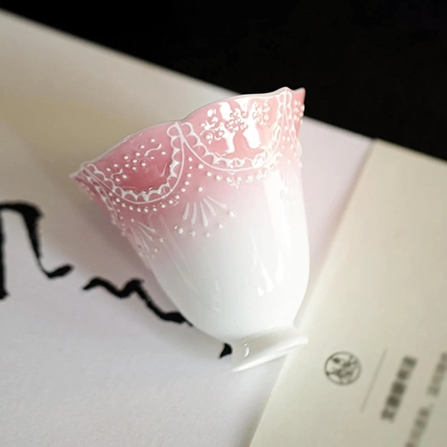 Pink-and-white scalloped ceramic tea cup at an angle