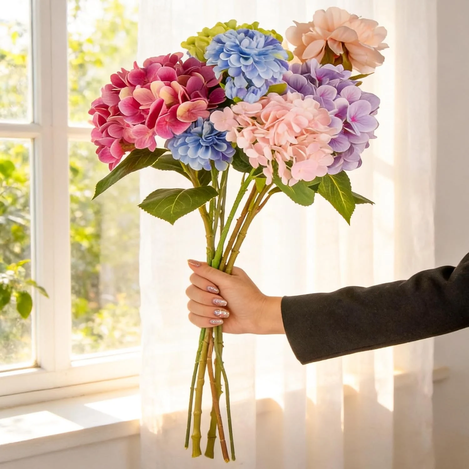 Long multicolor hydrangea-style stems held near a window