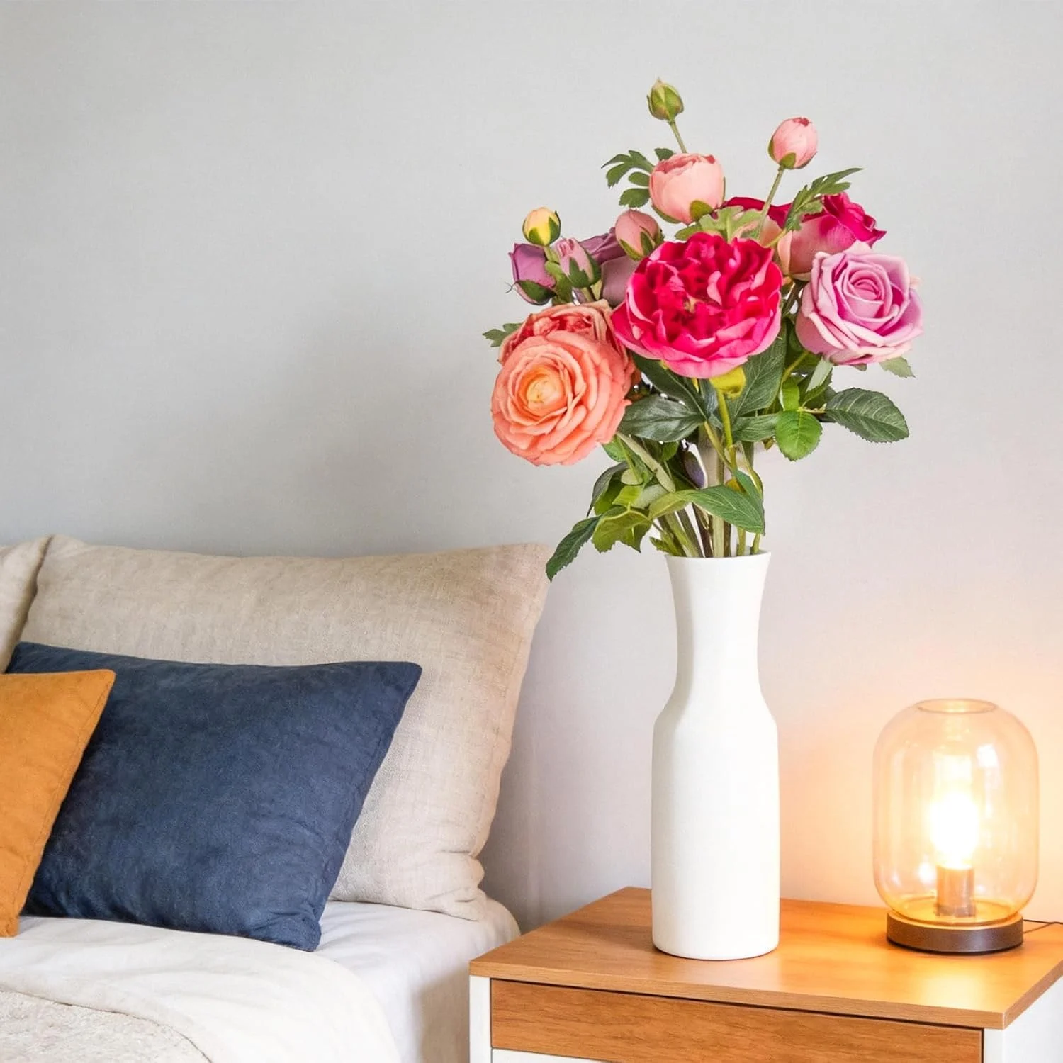 Colorful rose arrangement in a white vase beside a sofa