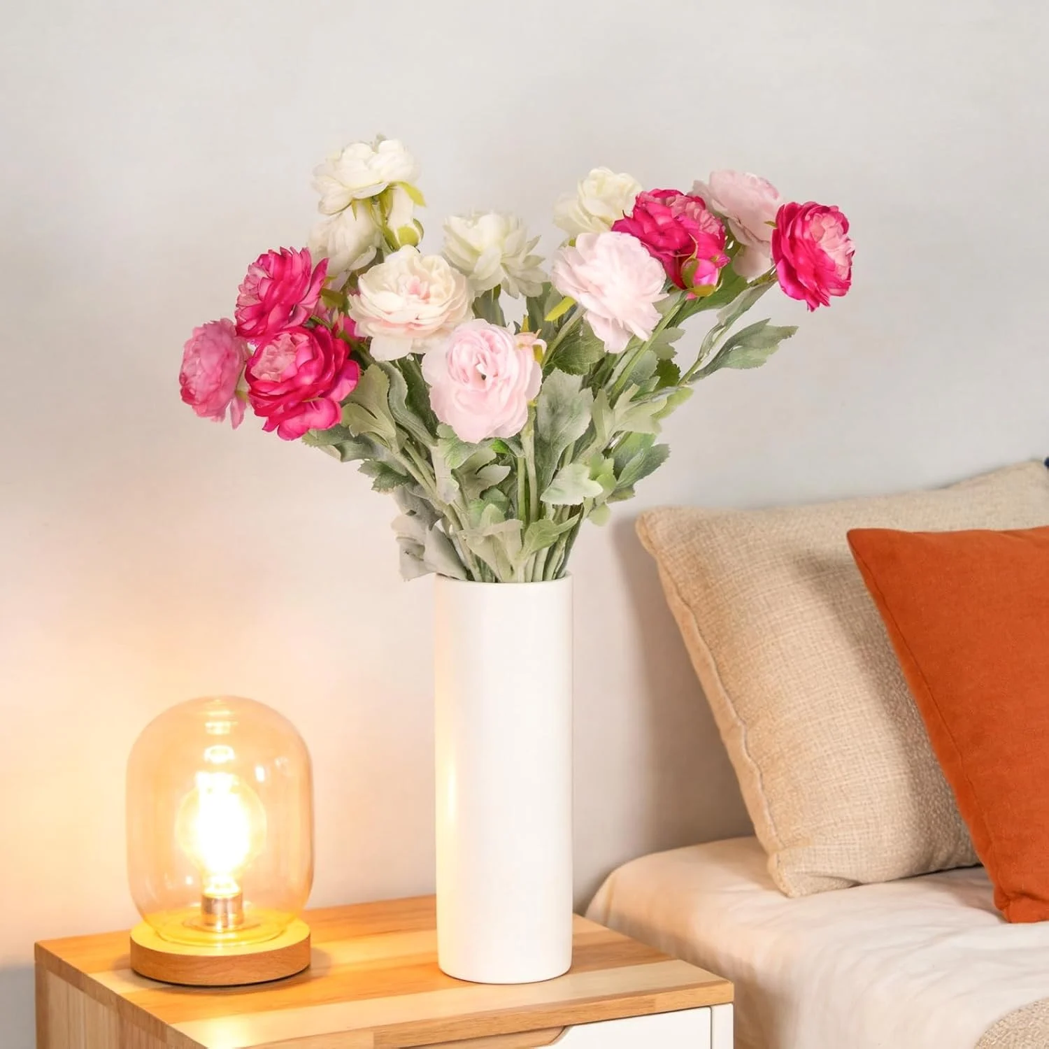 Magenta and ivory flowers displayed in a white bedside vase