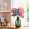 Colorful hydrangeas arranged in a green glass bottle on a shelf KAMMAK 8KPFZH002 home decor product styled home decor setting image 5
