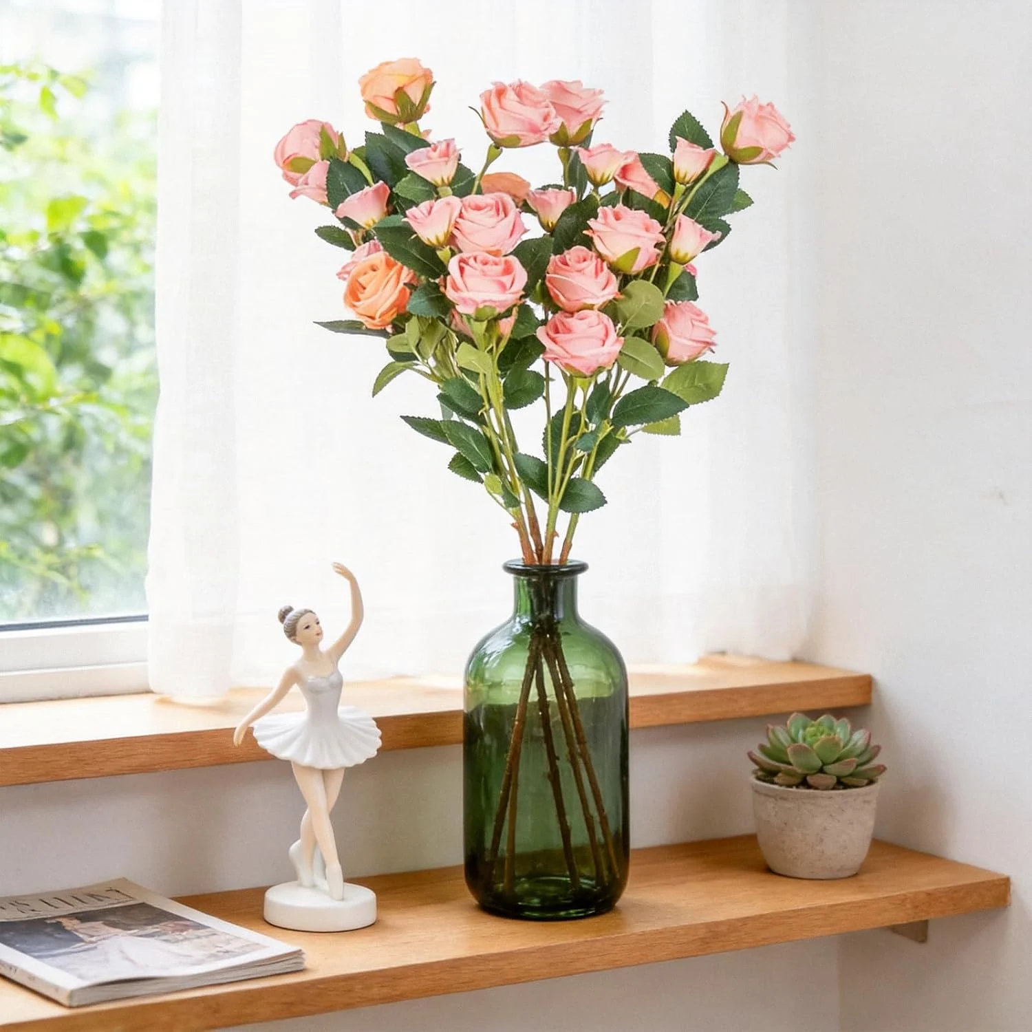 Pink rose stems arranged in a green glass bottle on a shelf