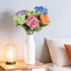 Bright mixed hydrangeas in a white vase beside a sofa KAMMAK 8KPFZH009 home decor product decorative craft detail image 7