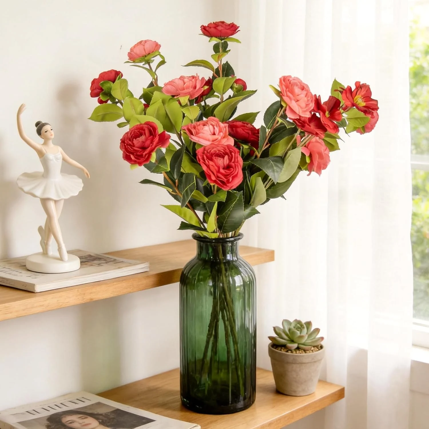 Red and coral flower arrangement in a green glass bottle