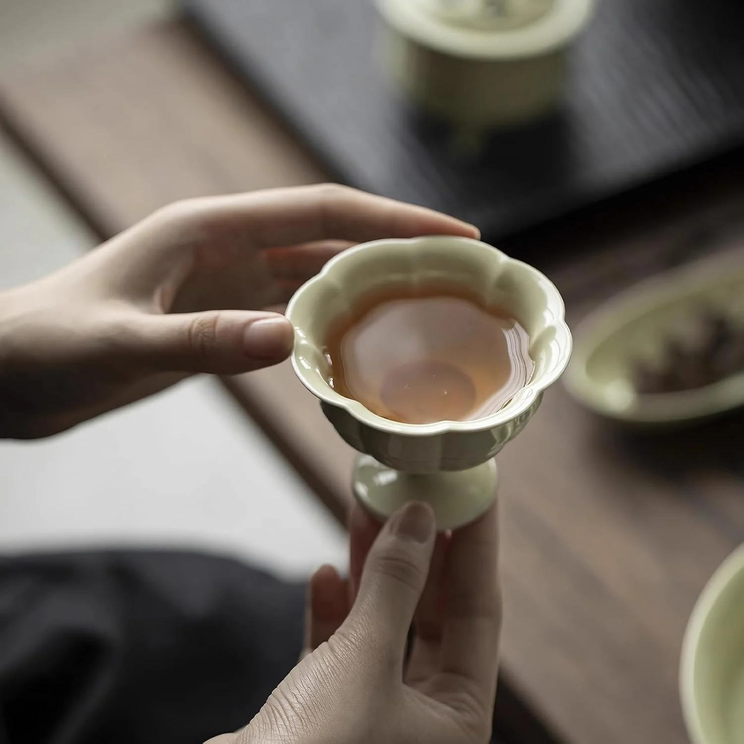 Reed green porcelain tea cup held in one hand