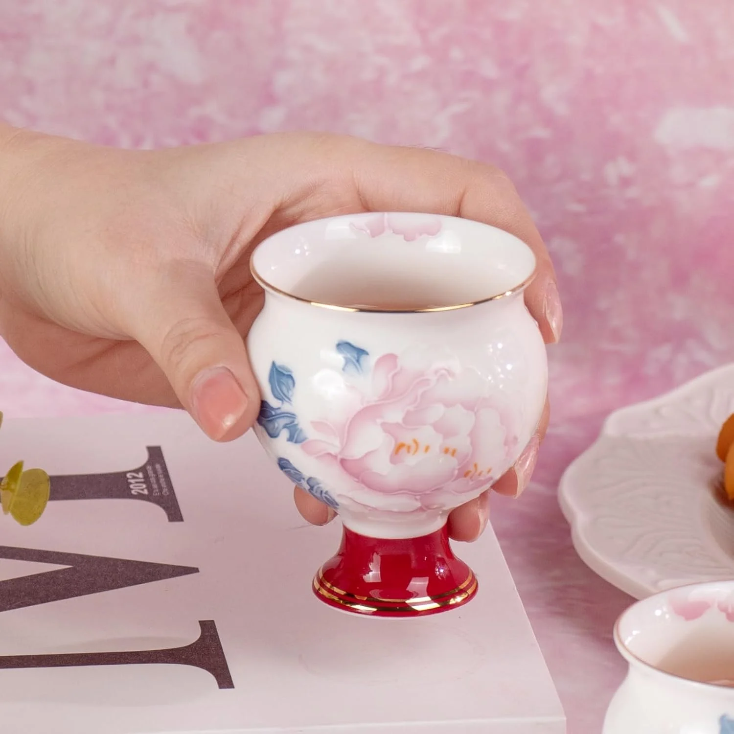 Rounded peony porcelain tea cup held in one hand