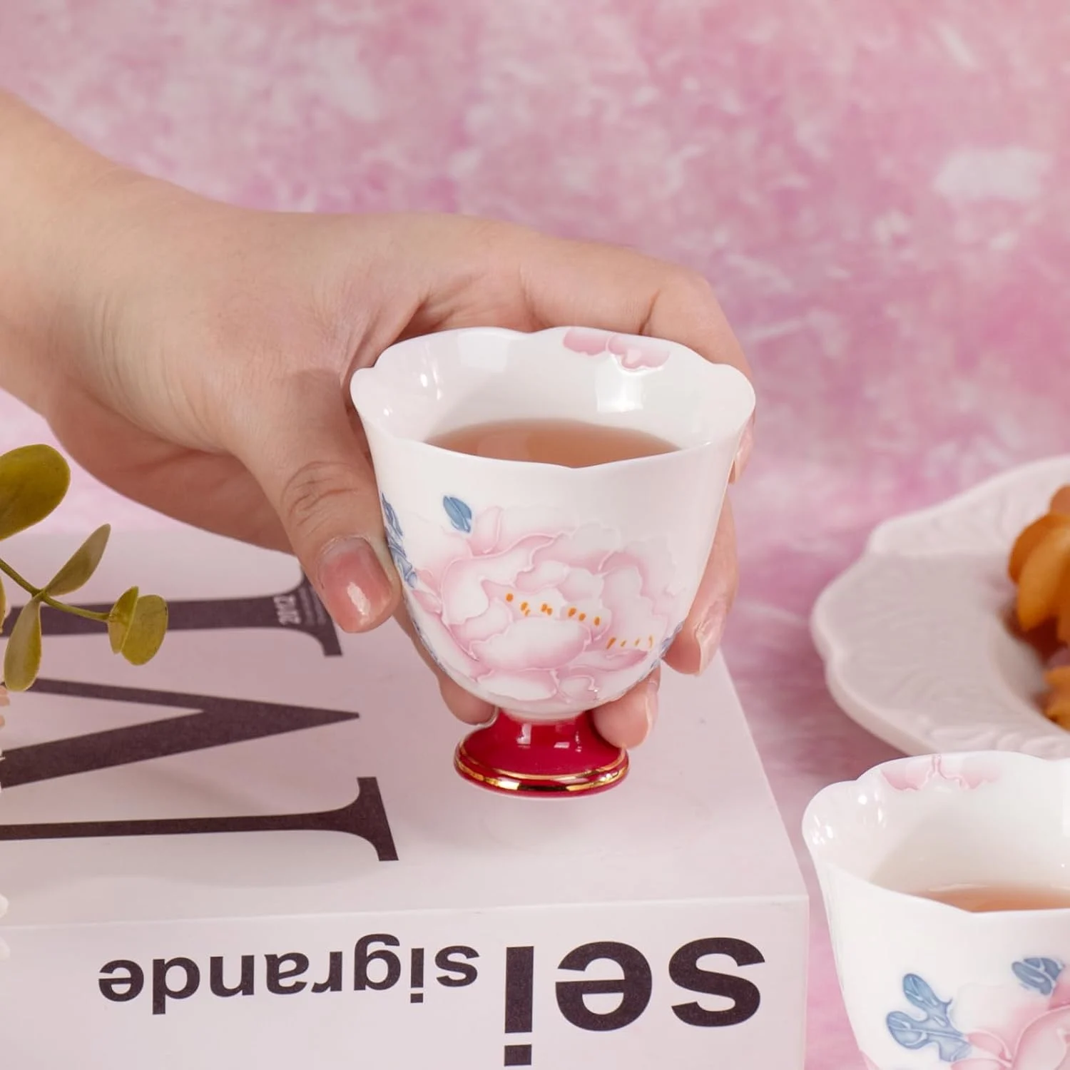 White peony porcelain tea cup held in one hand