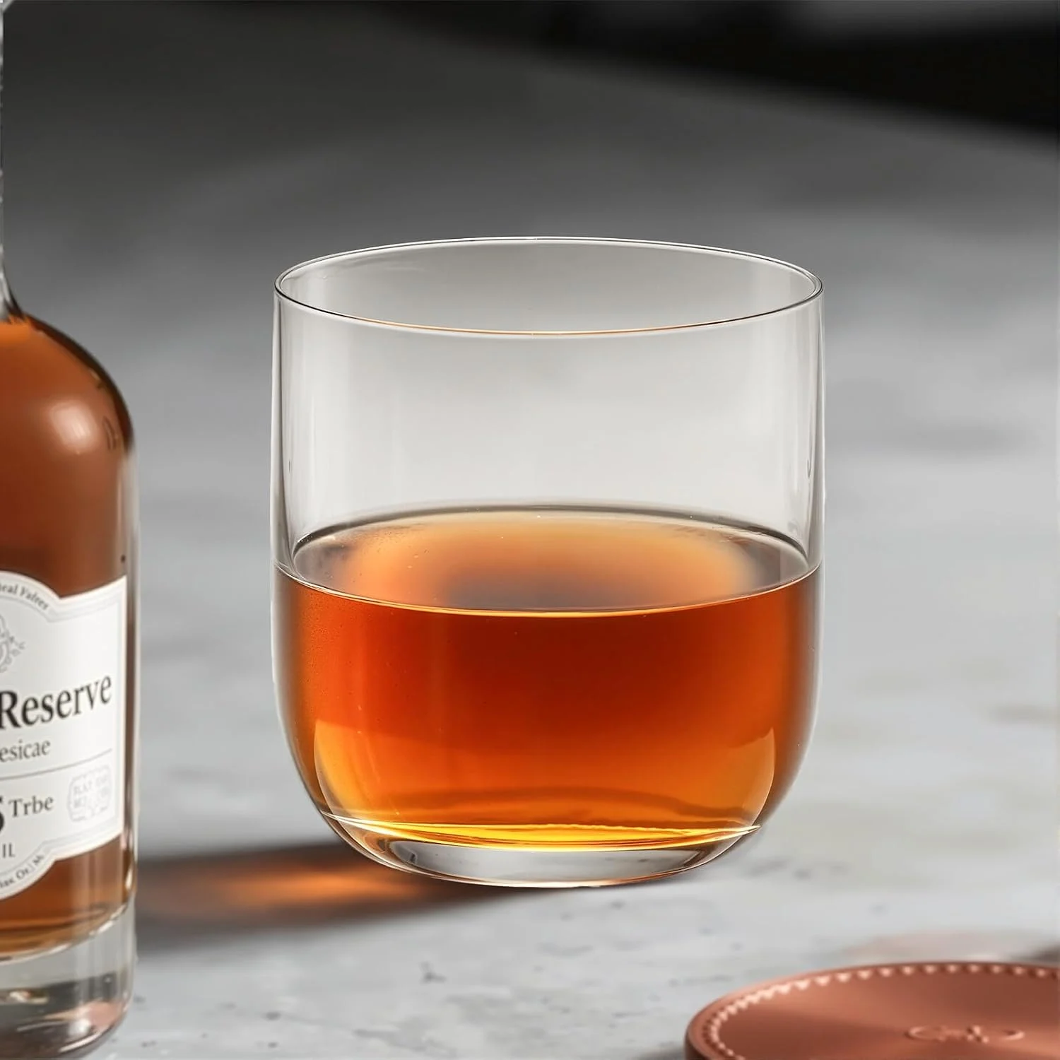 Straight-sided crystal whiskey tumbler beside a bottle