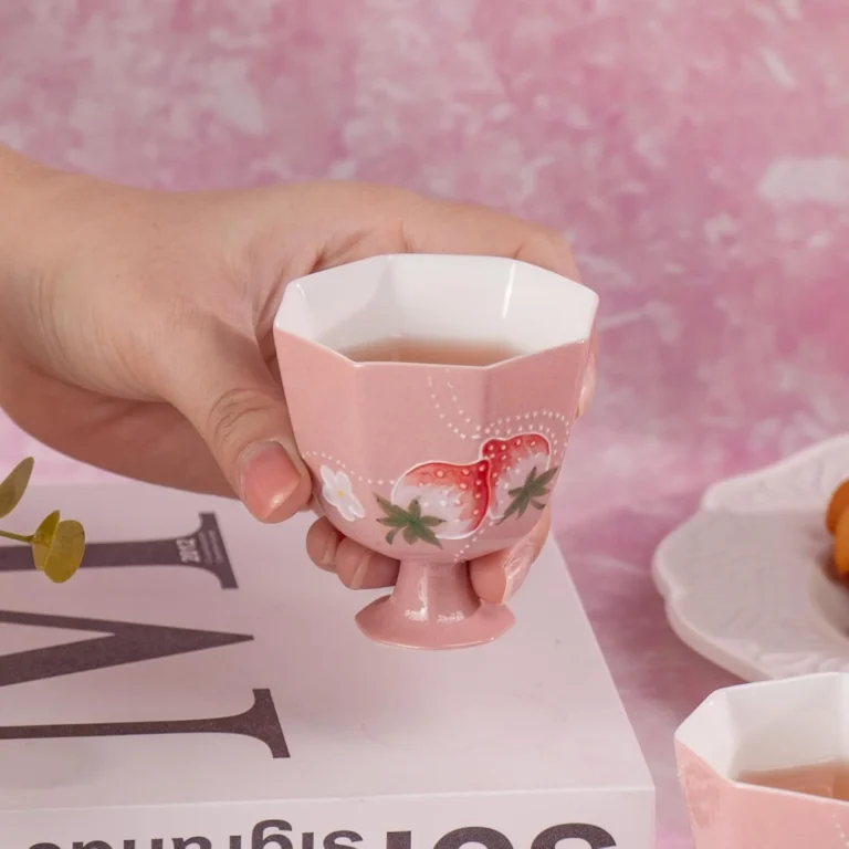 Pink faceted strawberry tea cup held in one hand