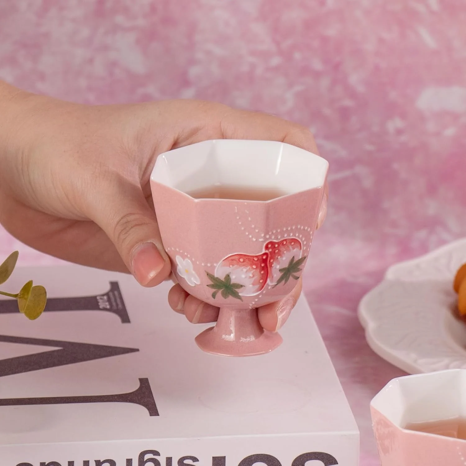 Pink faceted strawberry tea cup held in one hand