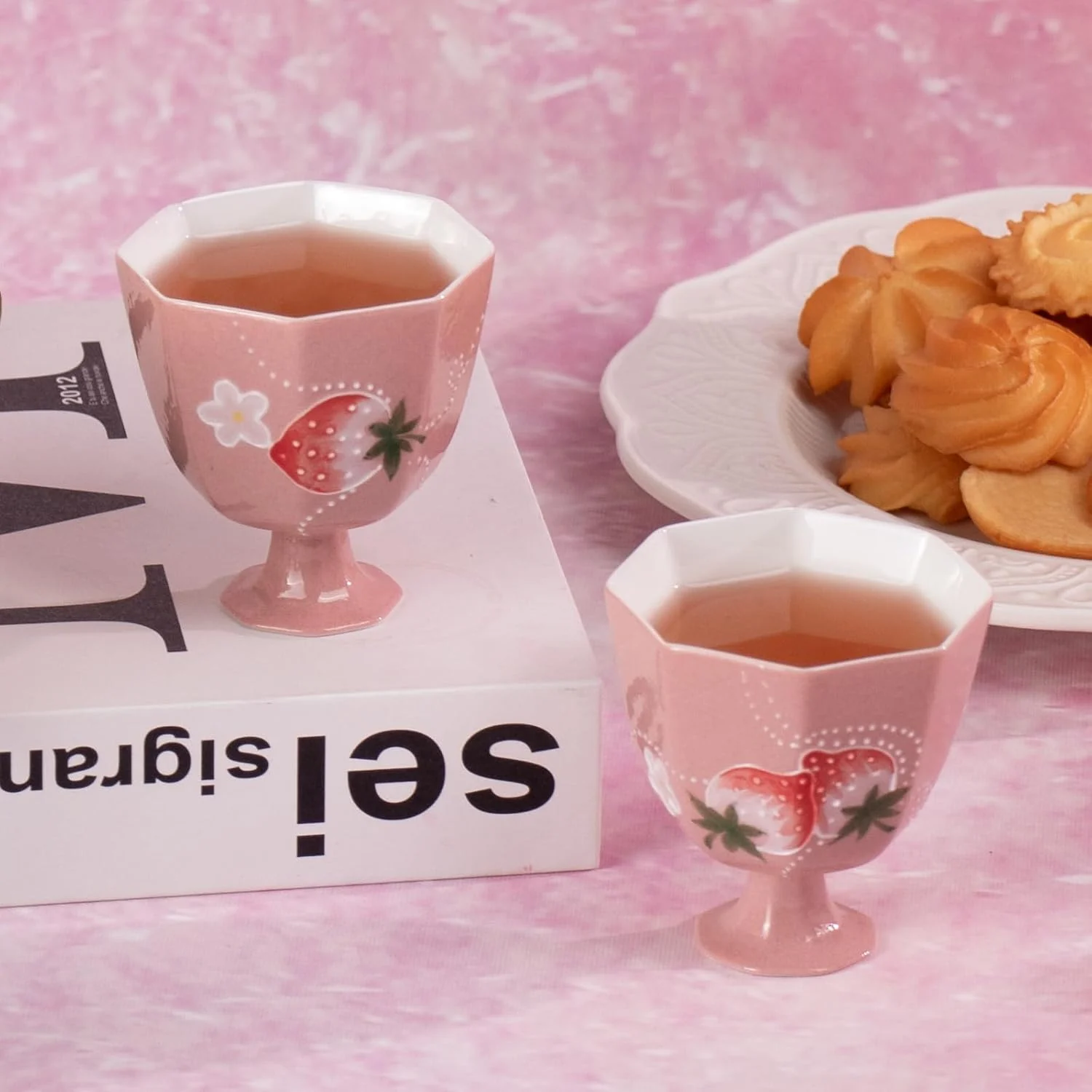 Two pink strawberry porcelain tea cups together