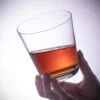 Tapered crystal whiskey glass held with an amber drink KAMMAK 7KPSP772N whiskey glasses styled on dining table image 5