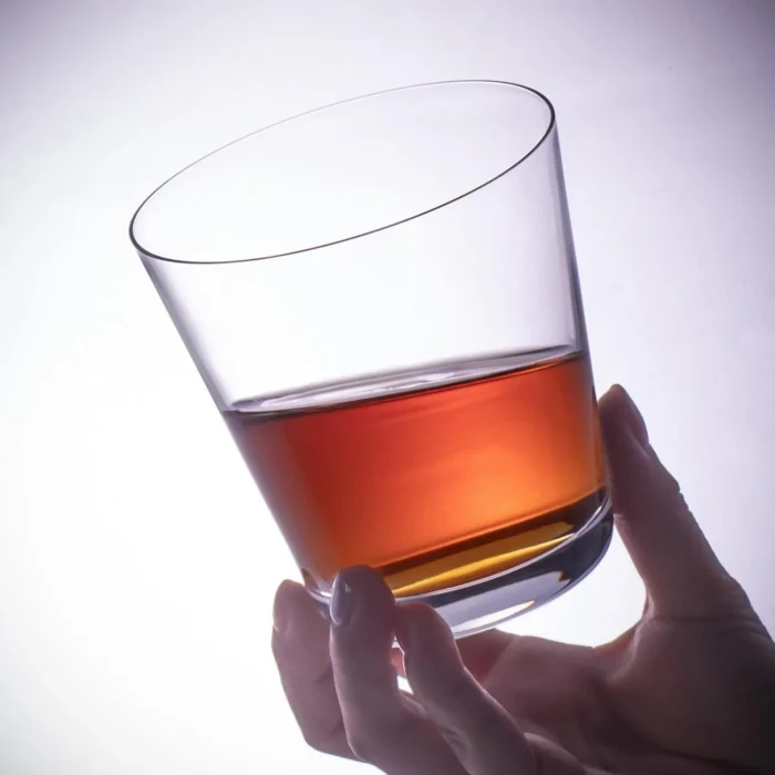 Tapered crystal whiskey glass held with an amber drink KAMMAK 7KPSP772N whiskey glasses styled on dining table image 5