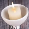 Round white ceramic plate holding a pillar candle KAMMAK 7KPSP495N pillar candles close-up material texture detail image 4