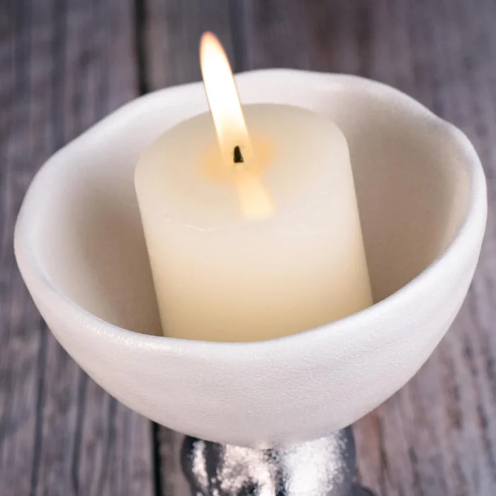 Round white ceramic plate holding a pillar candle KAMMAK 7KPSP495N pillar candles close-up material texture detail image 4