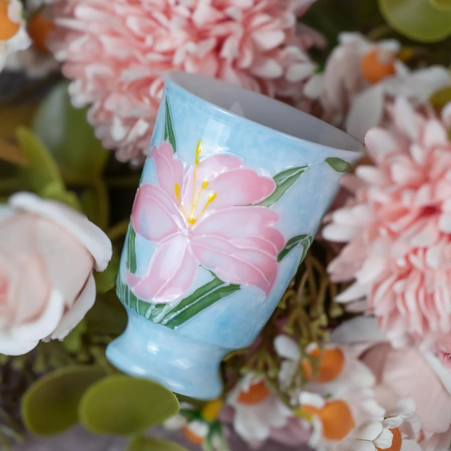 Pink lily KAMMAK footed tea cup shown among soft flowers