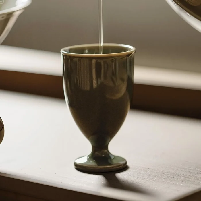 Tea being poured into an olive green KAMMAK high-footed cup KAMMAK 7KPSP694N+695N ceramic cup and saucer close-up material texture detail image 4