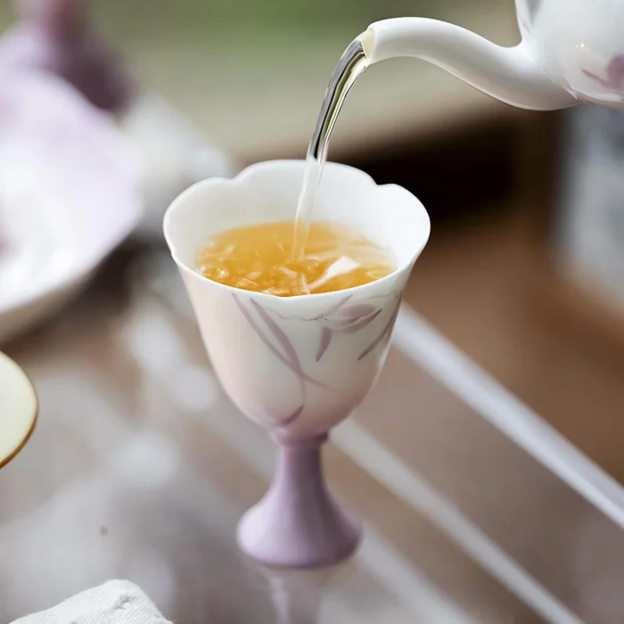 Tea being poured into a lavender KAMMAK scalloped footed cup KAMMAK 7KPSP686N+687N ceramic cup and saucer shape and proportion detail image 3