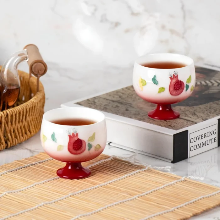 Two KAMMAK 698N pomegranate tea cups filled beside a woven basket KAMMAK 7KPSP698N ceramic cup and saucer shape and proportion detail image 3