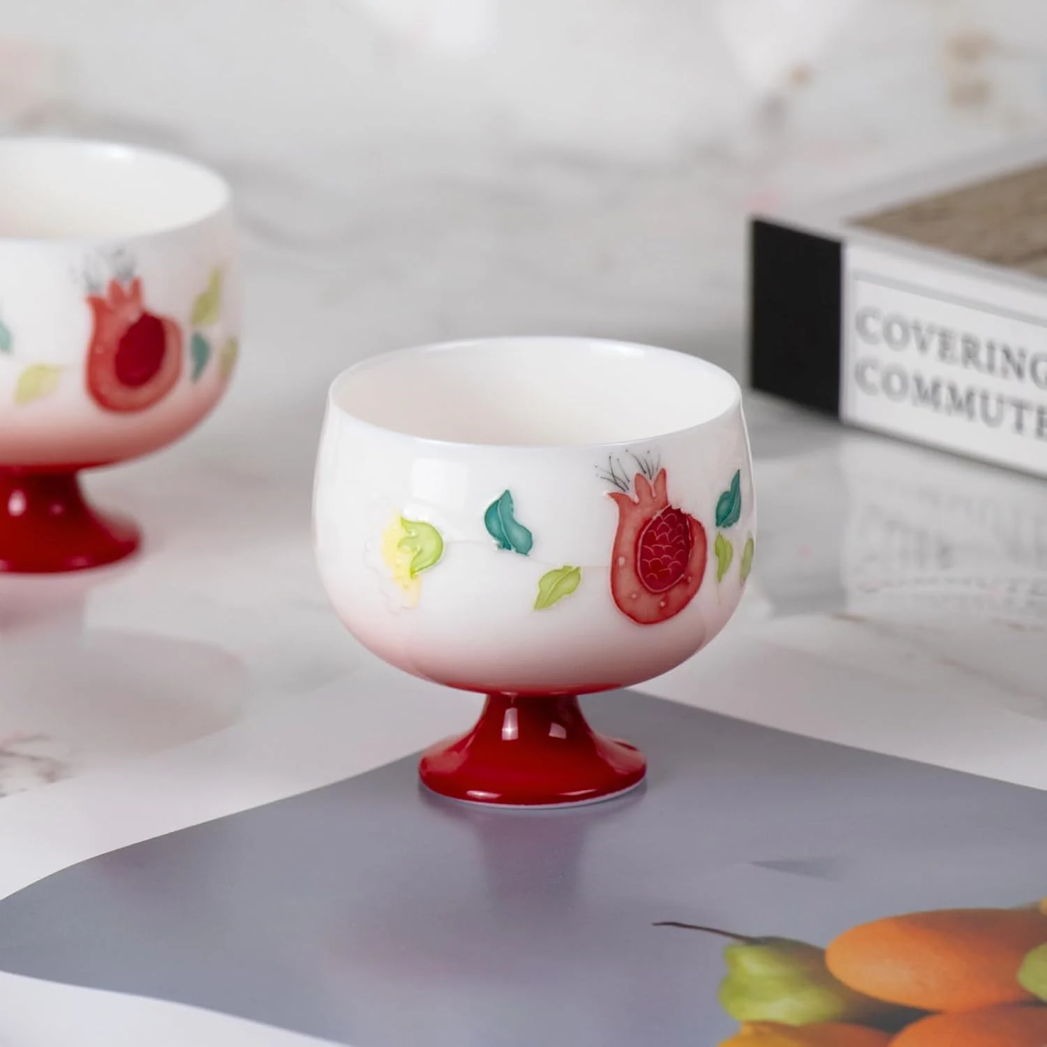 Single KAMMAK 698N pomegranate tea cup displayed beside books