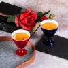 Red and navy KAMMAK footed cups filled with tea beside roses KAMMAK 7KPSP680N+681N ceramic cup and saucer shape and proportion detail image 3