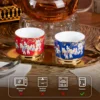 Red and blue KAMMAK porcelain cups beside a teapot with care icons KAMMAK 7KPSP424N ceramic cup and saucer shape and proportion detail image 3