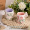 KAMMAK floral tea mugs displayed together among soft flowers KAMMAK 7KPSP434N ceramic cup and saucer side angle view showing silhouette