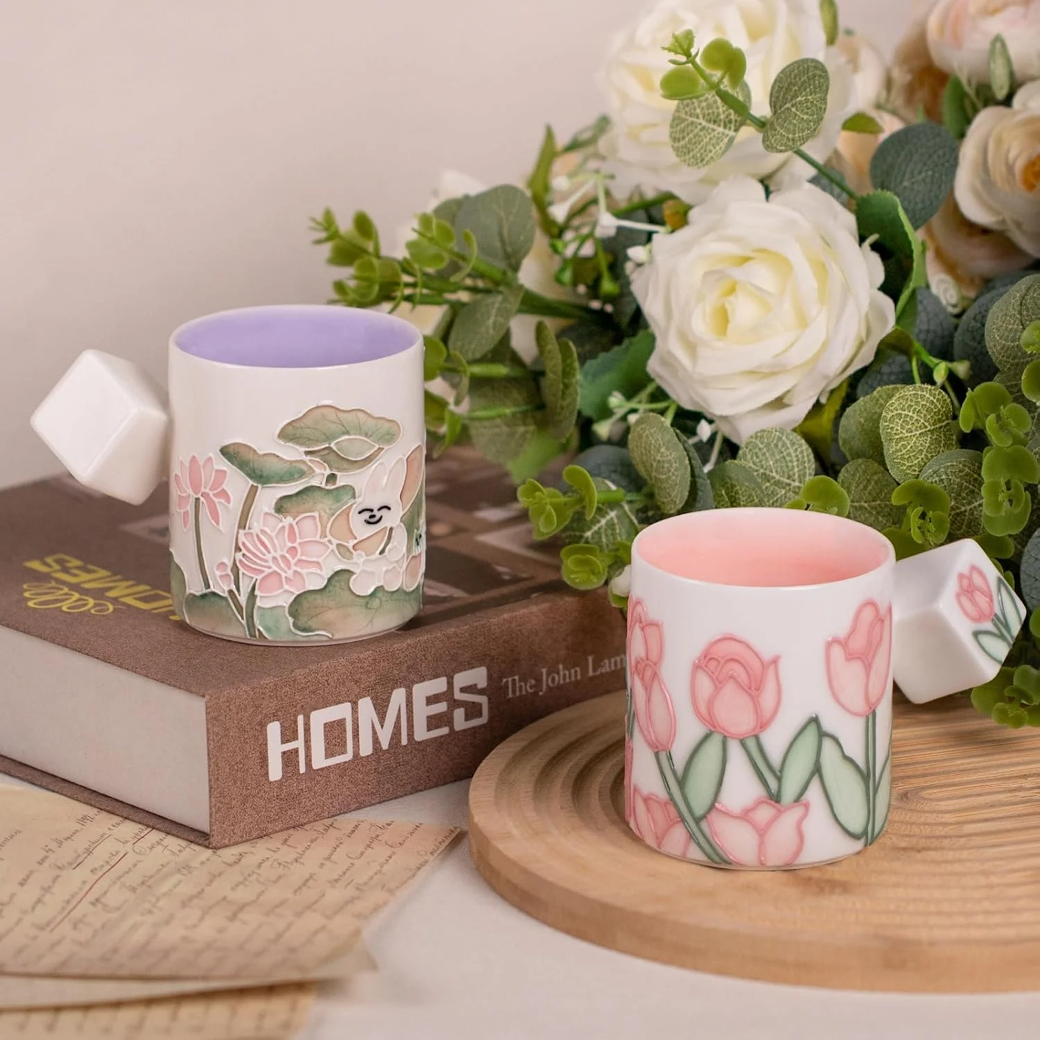 KAMMAK floral ceramic mug pair styled on books and a wood stand